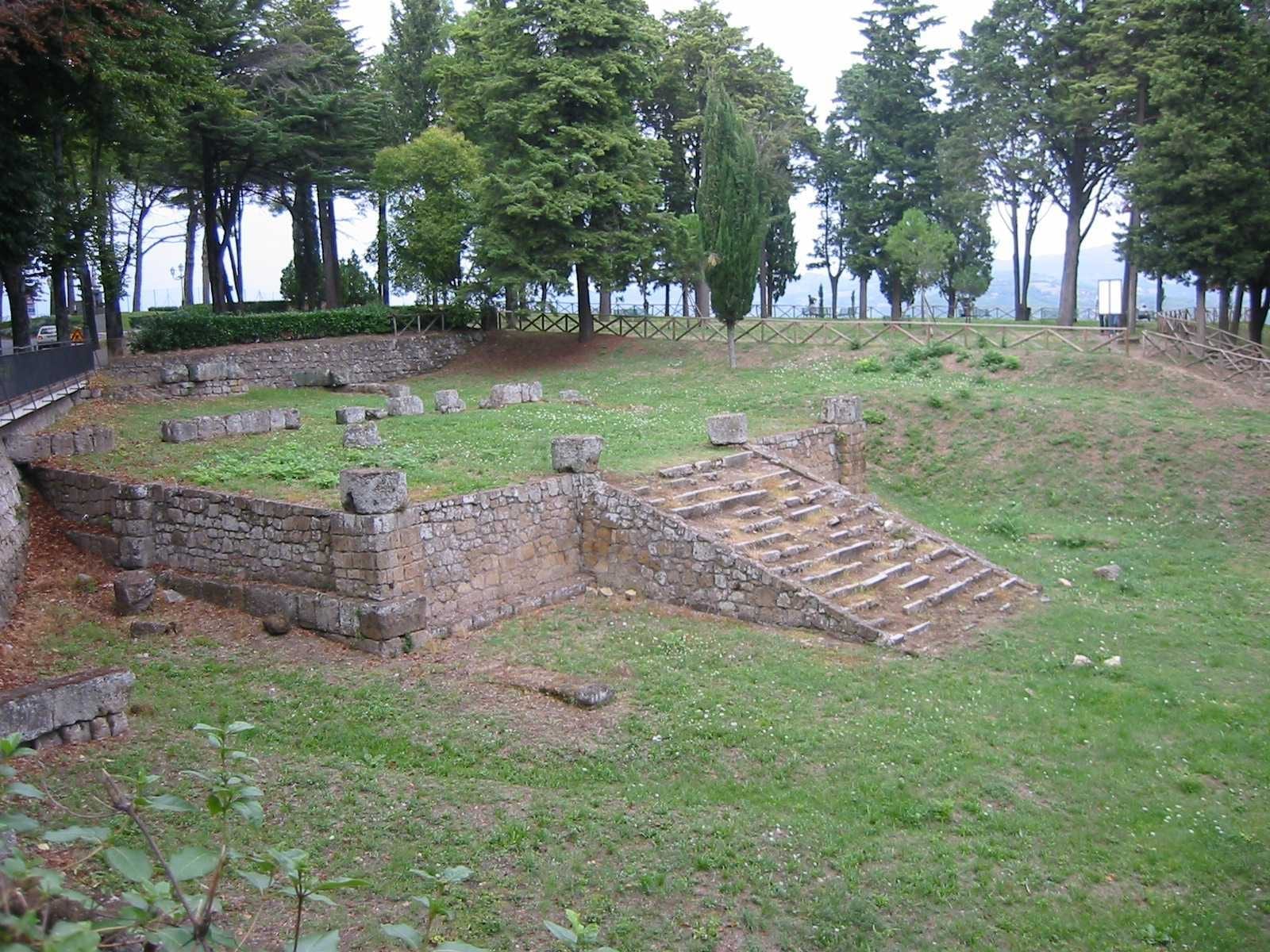The exposed stone foundations, stairway, and column bases of an ancient Etruscan temple on a terraced site.