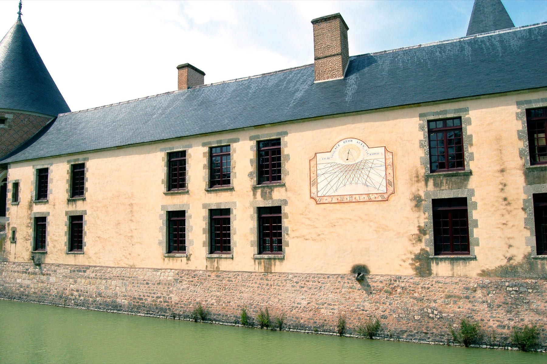 A weathered stone sundial mounted on a Renaissance facade at the Chateau de Chamerolles, France.